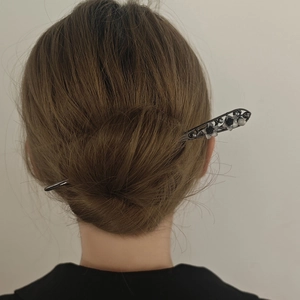 Elegant hair pin with floral detail and beads shown on a woman's hair bun