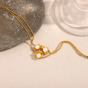 Close-up of 18K gold plated bead bracelet with three pearl-centered flower charms
