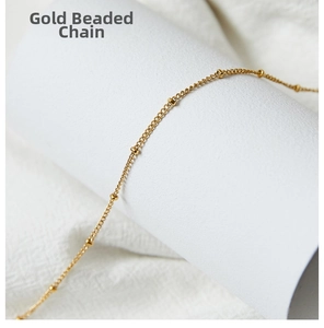 Detail of 18k gold-plated beaded link chain necklace on elegant white jewelry display