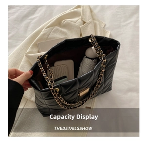 Macro view of black quilted tote bag showcasing large capacity with phone and umbrella