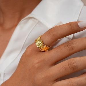 Détail d'une bague fleur géométrique dorée avec texture de lave sur le doigt