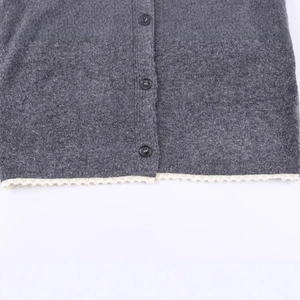 Grey knit cardigan featuring circular black buttons and white wavy lace hem detail