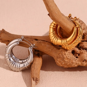 Detailed view of gold and silver hollow striped hoop earrings on natural wood branches