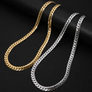 Gold and silver stainless steel flat Cuban link necklaces on black leather texture