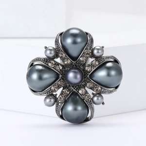 Detailed close-up of a dark grey baroque cross brooch with water drop pearls and crystals