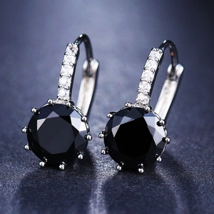 Macro view of silver earrings featuring a large black faceted zircon and diamond inlay