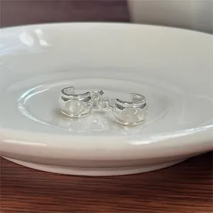 Macro view of C-shaped 925 silver earrings featuring an iridescent moonstone gem