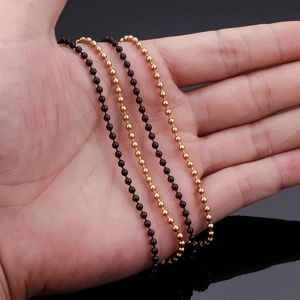 Detailed view of black and gold stainless steel bead chains held by a hand