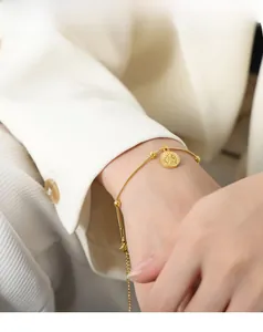 Detailed view of 18k gold plated snake chain bracelet with embossed portrait coin pendant
