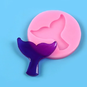 Pink silicone mold and purple mermaid tail fondant cake topper on blue background