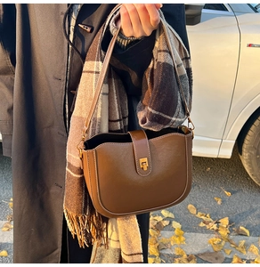 Detail of vintage brown leather saddle bag with gold buckle and fine stitching