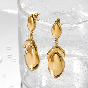 Polished gold geometric teardrop earrings hanging on a water droplet glass background