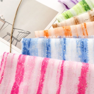 Detail of soft tie-dye linen texture with gold foil accents and frayed edges