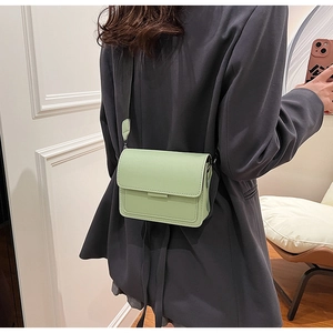 Rear view of a sage green rectangle crossbody bag with a wide strap on a model