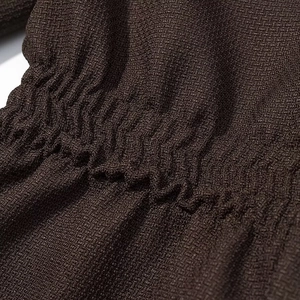 Close-up of deep brown textured fabric featuring detailed elastic shirring craftsmanship