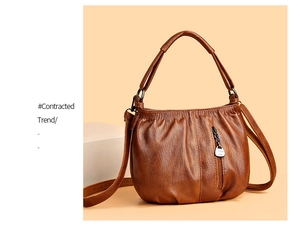 Detailed view of the tan pleated shoulder bag featuring a silver logo pendant and zip pocket