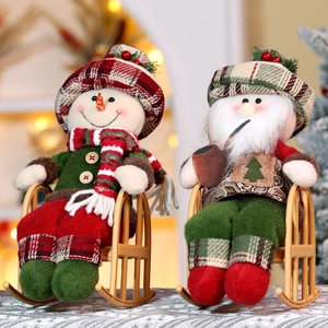 Close-up of Santa and snowman plush dolls with red plaid fabric on rocking chairs