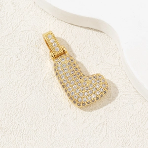 Gold plated letter J pendant necklace with zircon stones on an elegant background