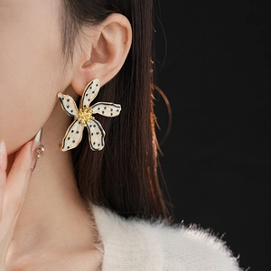 Close-up of vintage floral stud earring with black dots on white petals worn by model
