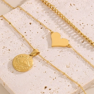 Dettaglio di collane d'oro a strati con ciondolo a cuore e pendente con occhio inciso