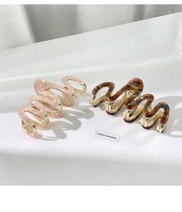 Detail of wavy acetate hair claws in pink marble and dark tortoiseshell with gold clips