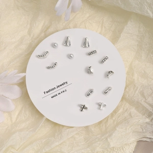 Chic silver stud earring set featuring plane, moon, and pearl designs on display card
