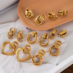 Detail of assorted 18K gold plated stainless steel hoop earrings and heart studs on wood