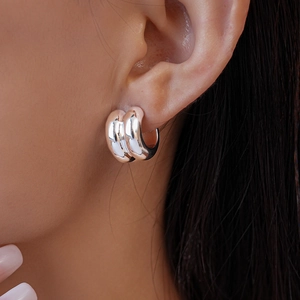Macro shot of a woman wearing double-layer polished silver hoop earrings with high shine