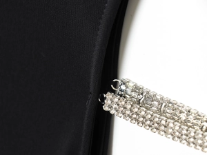 Détail macro des bretelles en strass argentés sur le tissu noir tissé d'une robe