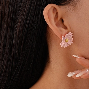 Detailed view of pink floral earrings with golden stamen on a model's ear