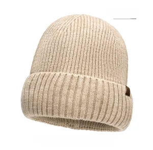 Detailed close-up of beige ribbed knit beanie featuring a small side leather logo label