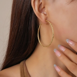 Nahaufnahme von matt vergoldeten 18k Creolen an einem Model für einen edlen Look