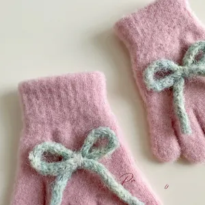 Close-up of pink plush knitted gloves with soft wool texture and a cute blue knit bow