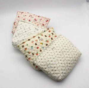 Detailed stack of quilted cotton makeup bags with floral and cherry patterns