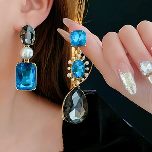 Detail of vintage gold earrings with blue and black gemstones and white pearls