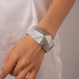 Detailed view of silver irregular faceted cuff bracelet with radial texture on wrist