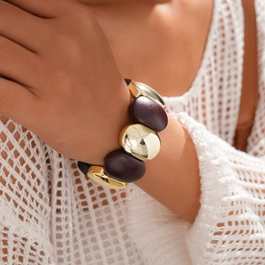 Gros plan d'un bracelet en perles acryliques avec sphères dorées et perles violet foncé