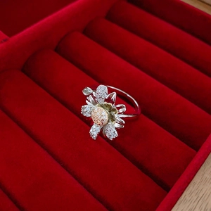 Macro detail of a floral ring with silver petals and pavé diamonds in a red velvet box