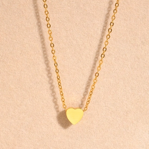 Minimalist gold heart pendant necklace for women with fine chain on beige background