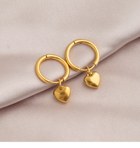 Detail of gold heart earrings on satin background showing smooth finish and metal luster
