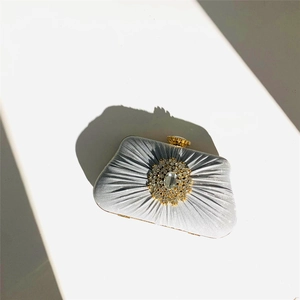 Macro shot of silver pleated satin evening clutch with radiant rhinestone decoration
