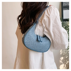 Detailed blue woven texture on a fashion crescent armpit bag carried by a model
