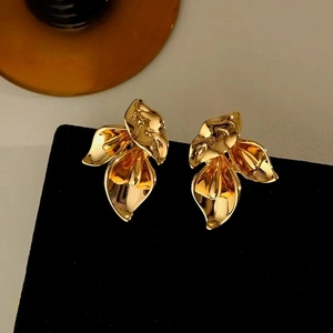 Detailed view of 3D gold petal floral stud earrings on black velvet stand