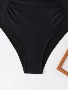 Detail view of black halter swimsuit featuring ruching texture and smooth elastic fabric