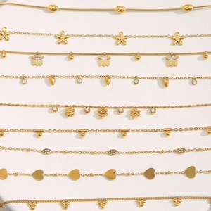 Détail de chaînes en acier plaqué or 18K avec pendentifs cœur et fleur en zircon