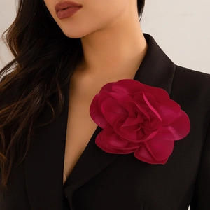 Detailed close-up of a burgundy floral brooch styled on a professional black blazer