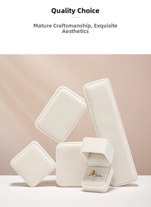 Minimalist white velvet jewelry boxes with an open ring box showing a yellow gem ring