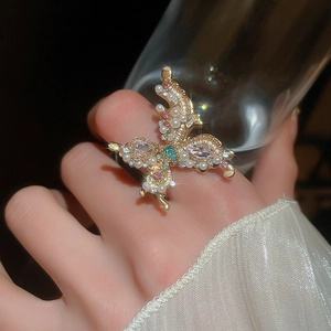 Macro shot of butterfly ring featuring pink crystals and pearls on gold frame