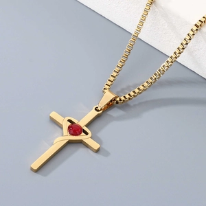 Detailed macro view of golden cross necklace with red heart stone and square link chain