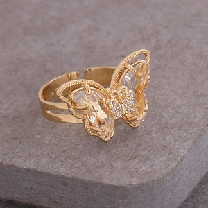 Macro shot of gold butterfly ring with crystals on a textured stone surface